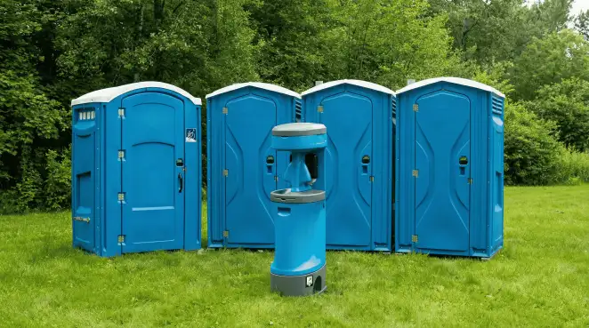 Four blue portable toilets and a matching hand washing station on grass near trees, a common sight at local outdoor events in Lincoln, NE